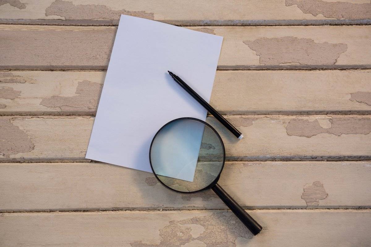 Loupe et stylo posés sur un document : l'audit blanc Qualiopi examine chaque preuve