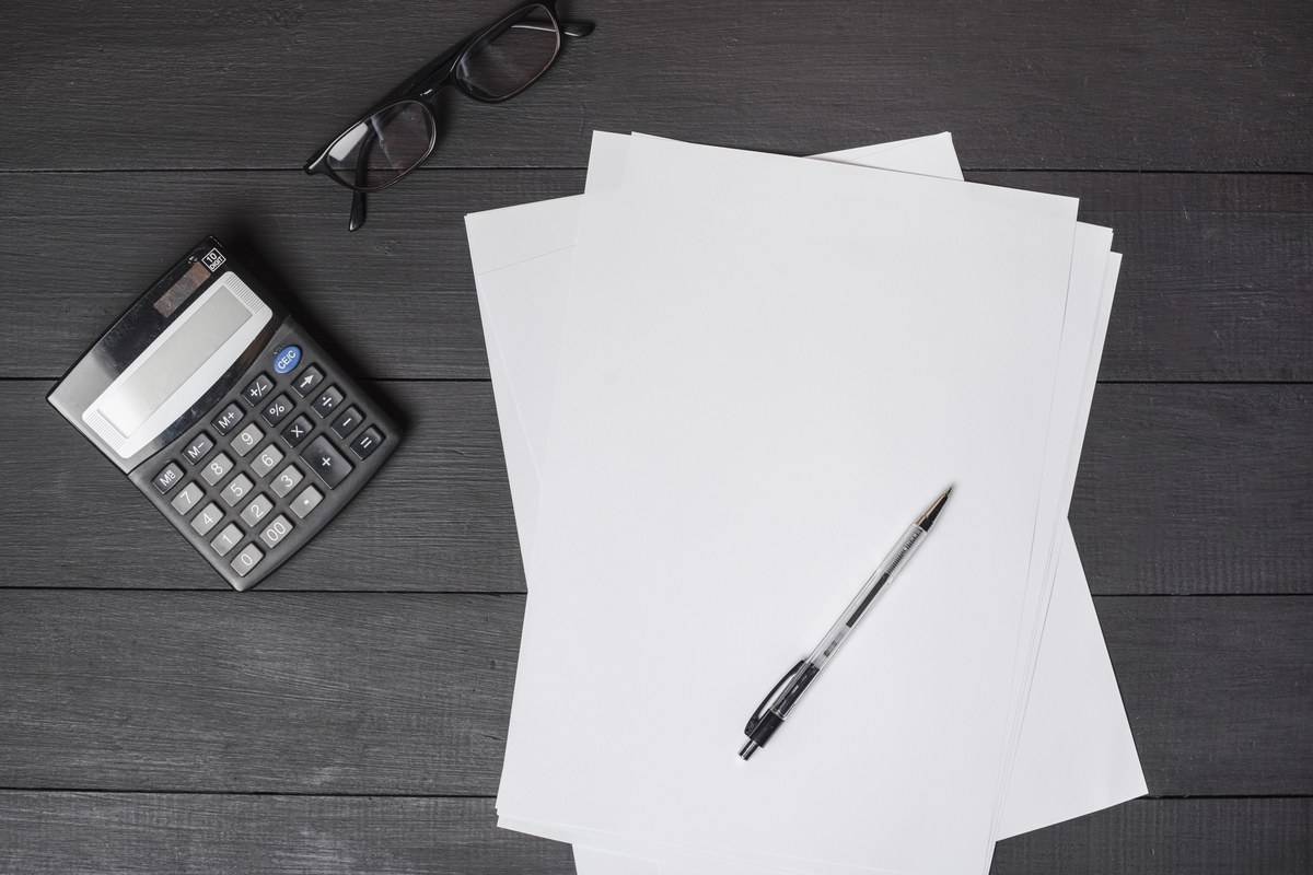 Feuilles blanches, calculatrice et stylo sur un bureau : comparer les devis des organismes certificateurs Qualiopi