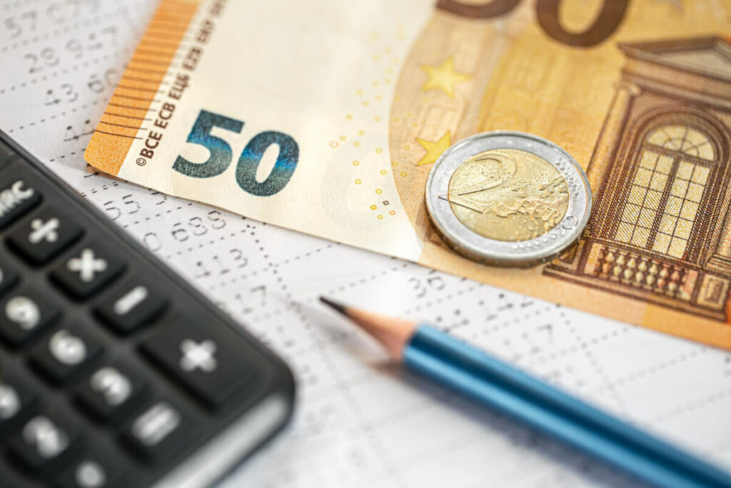 Billet de 50 euros, pièce, calculatrice et crayon posés sur un relevé de chiffres