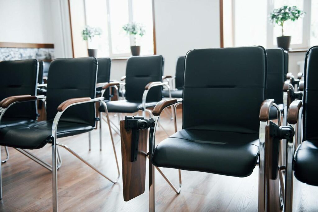 Salle de formation vide avec des chaises noires alignées, prête à accueillir des stagiaires